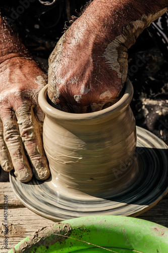 Hands of a potter shaping a clay pot on a potter wheel