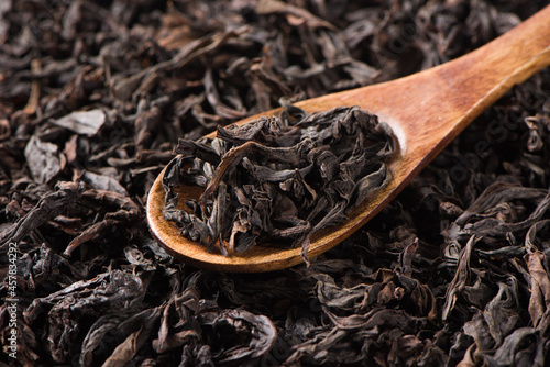 dry black tea leaf on spoon texture background photo