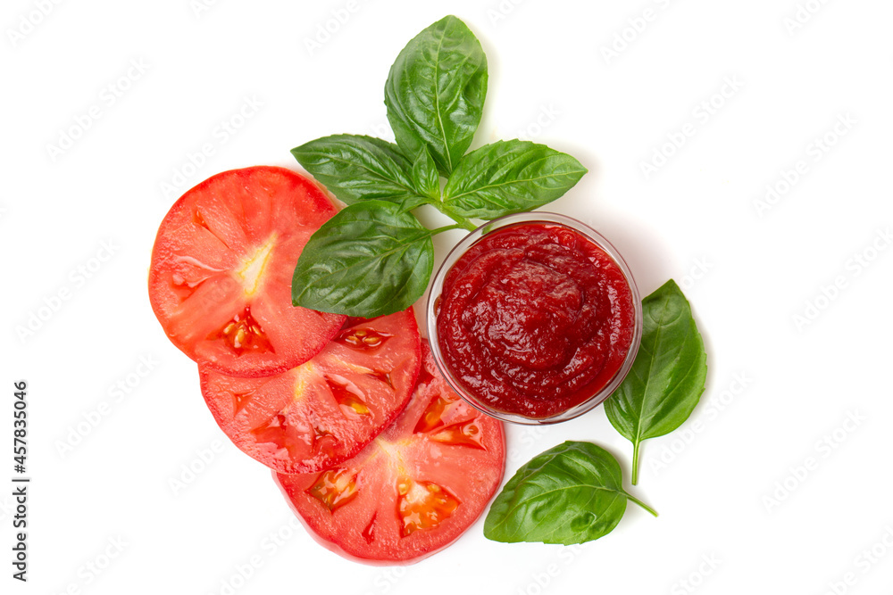 Ketchup (tomato paste) in a saucepan with basil leaves and tomato slices on a white background. Ketchup (tomato paste) in a saucepan with basil leaves and tomato slices on a white background.