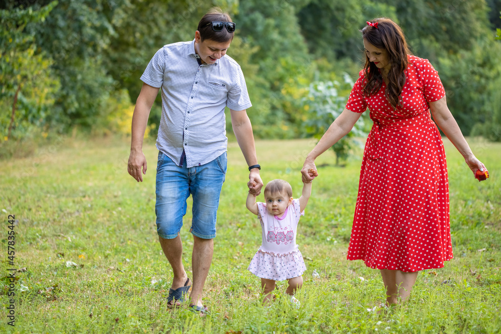 Happy young Family on the Walk in the Park. Mother, Father and Child Together the Joy on the Lawn and they have a Picnic. Concept Happiness of Family and Healthy Lifestyle.