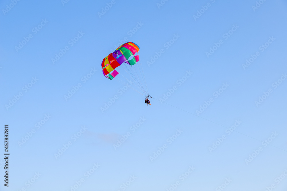 Parachute parasailing of tourists on a sunny day, adventure background with clear sky with no clouds Parachute parasailing of tourists on a sunny day, adventure background with clear sky with no clouds