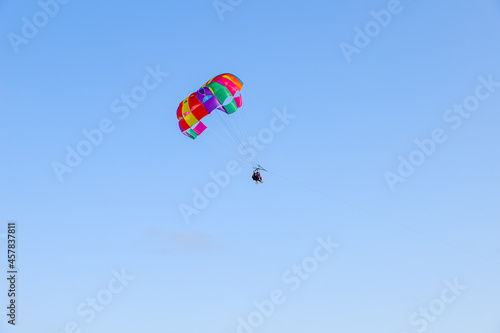 Parachute parasailing of tourists on a sunny day, adventure background with clear sky with no clouds
