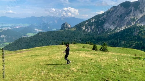 Female hiker in the Alps of Allgäu Bavaria Germany with hiking ploes with mountain panorama in the background, Hochalp close to Pfronten