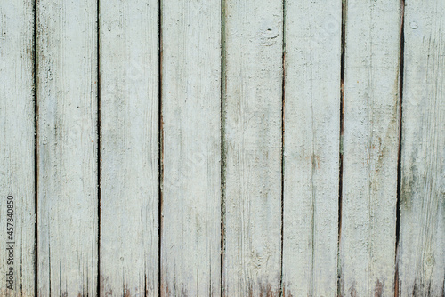 Wooden fence with green old paint, vertical boards, texture background exterior