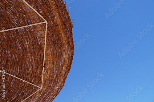 Beach straw umbrella in the blue sky.