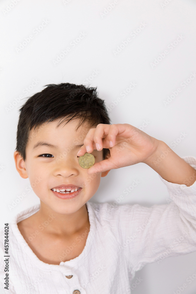A happy young asian boy holding an australian coin A happy young asian boy holding an australian coin