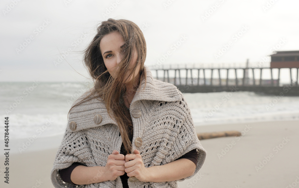 Autumn autdoor brunette woman portrait, woman dressed in knitted sweater posing against sea