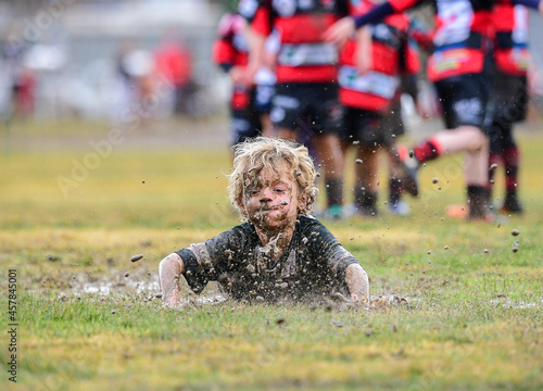 Junior rugby player belly slides in the mud photo