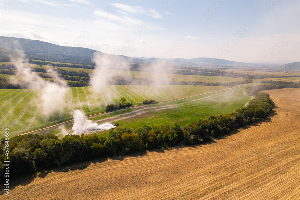 Aerial view of a tractor spreading lime on agricultural fields to improve soil quality after the autumn harvest. The use of lime powder to neutralize the acidity of the soil.