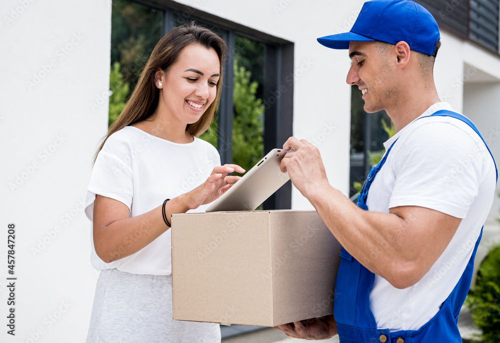 Young courier delivering goods to a young woman at home Young courier delivering goods to a young woman at home