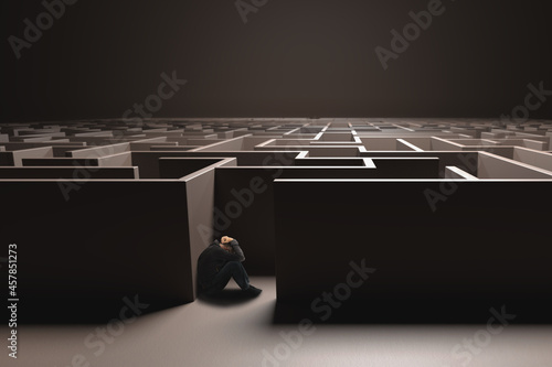 Unidentifiable man cowering in the entrance of a dark brown maze. Depression concept, hopelessness.
