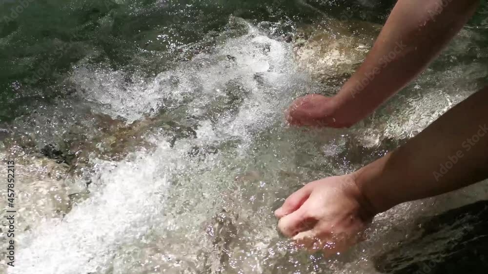 A man washes his hands with a mountain river close-up. A clean mountain river with a strong sweat, men's hands are collecting water. The concept of travel, recreation A man washes his hands with a mountain river close-up. A clean mountain river with a strong sweat, men's hands are collecting water. The concept of travel, recreation