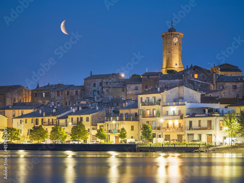 The Moon above city Marta on lake Bolsena in Italy in night lights