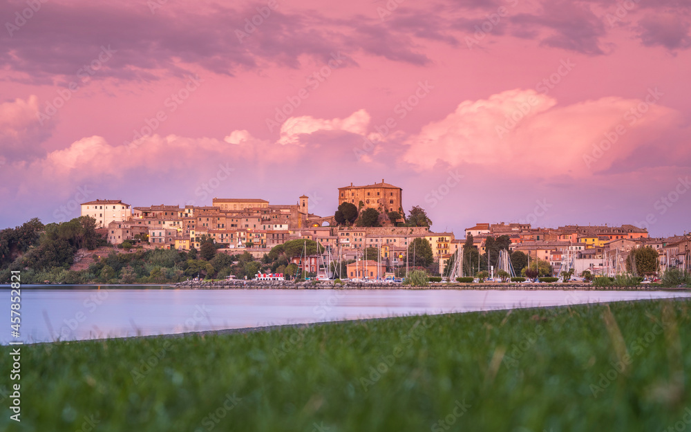 low point view through green grass to lake shore with view to city Capodimonte on lake Bolsena in Italy