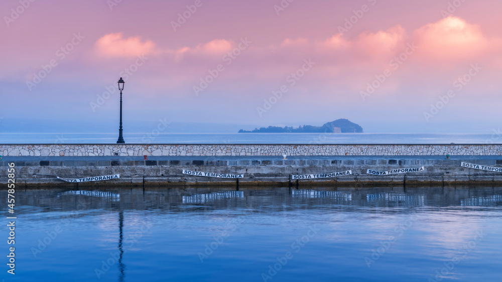 panoramic view to pier with street lighter and view to island Bisentina at lake Bolsena in Italy