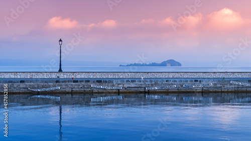 panoramic view to pier with street lighter and view to island Bisentina at lake Bolsena in Italy