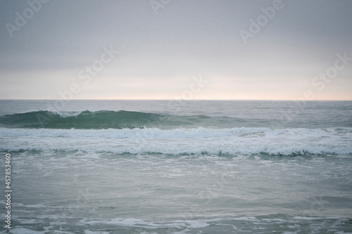 waves coming towards a beach at sunrise