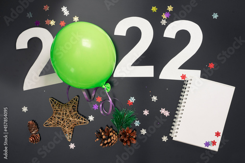 Layout on the theme of the New Year 2022 with numbers, a ball, toys and Christmas tree branches against a dark background.