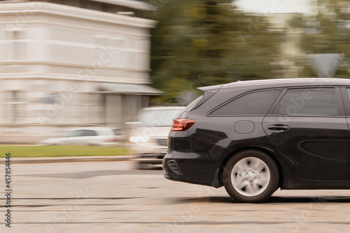 Side view of the back of a car driving on a paved street. Motion blur