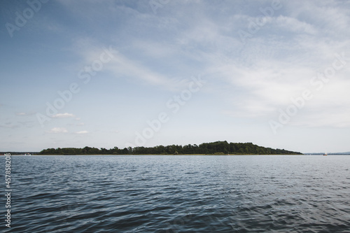 Small forest island in the middle of a lake under a blue sky © kvoronov