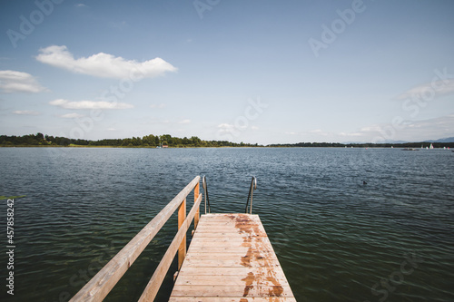 Beautiful wet wooden pontoon with access to the lake under the blue sky with clouds