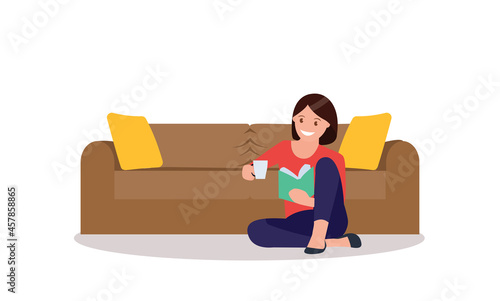 A young woman is sitting on the floor and reading a book.