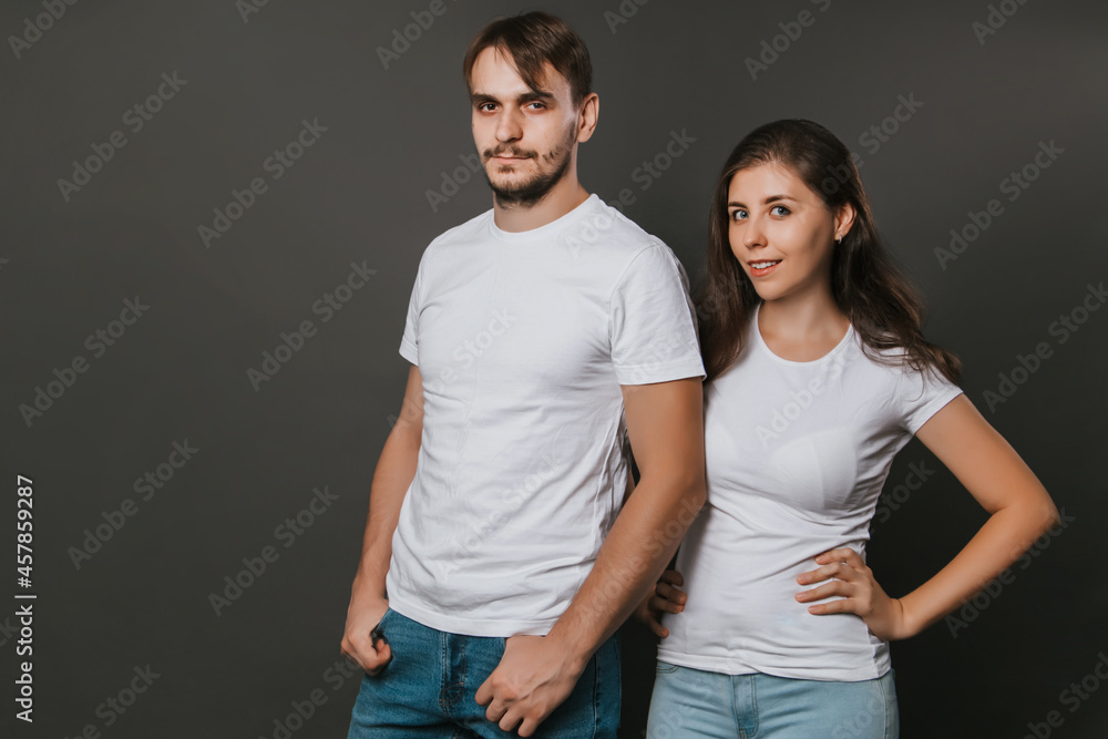 A young couple, a girl and a man in white blank t-shirts on a dark gray background. Mock-up. love story A young couple, a girl and a man in white blank t-shirts on a dark gray background. Mock-up. love story