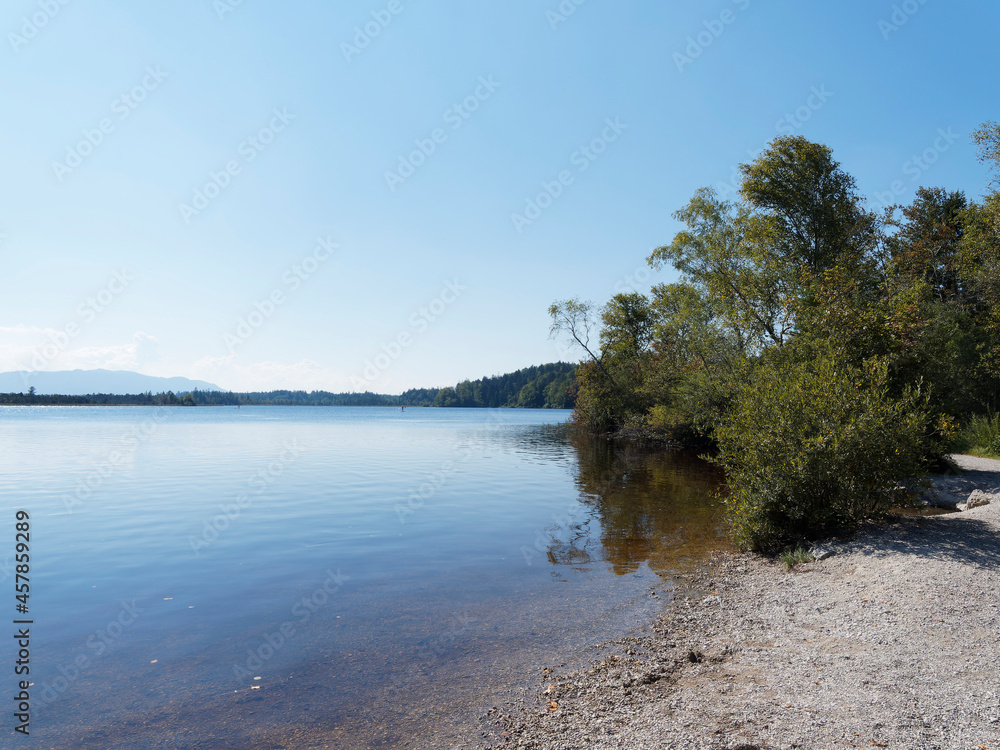 Kirchsee near Sachsenkam in Upper Bavaria, its moor lake amber and blue colored with popular small beach and bathing on wild shore