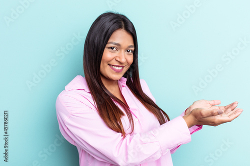 Young Venezuelan woman isolated on blue background holding a copy space on a palm.