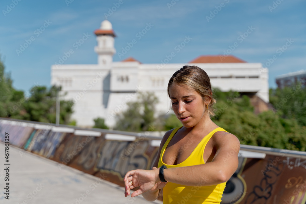 Caucasian woman in sportswear with digital watch counting heart beats. Horizontal view of fitness woman training outdoors.