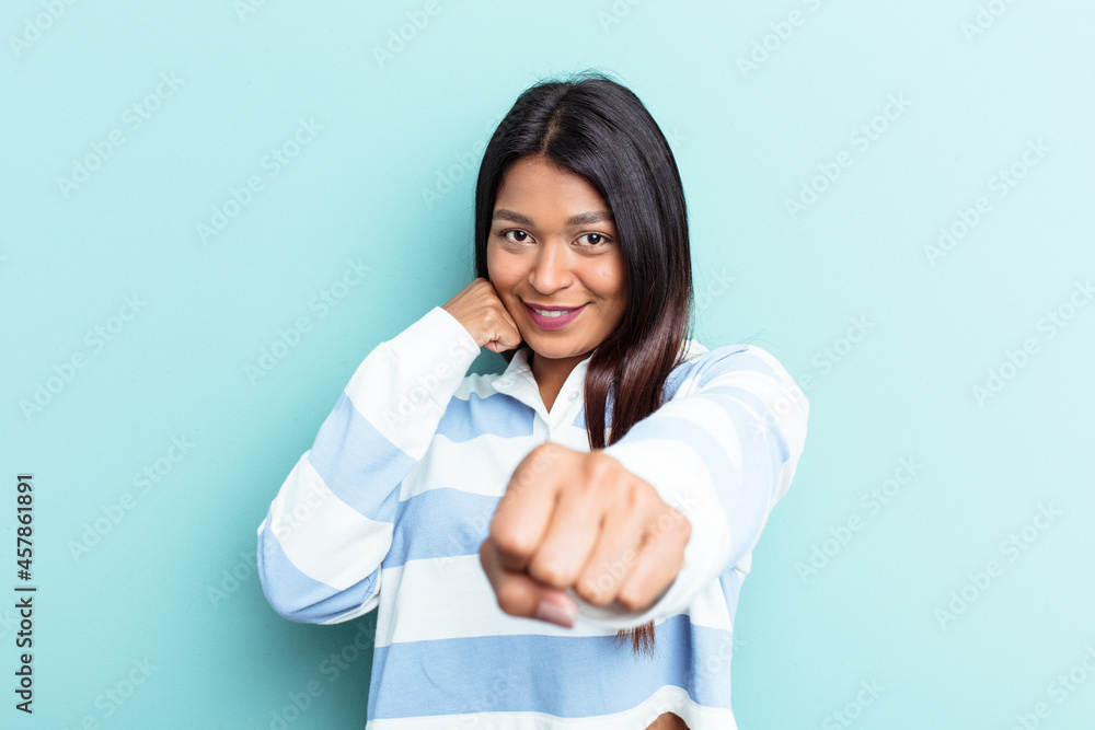 Young Venezuelan woman isolated on blue background throwing a punch, anger, fighting due to an argument, boxing. Young Venezuelan woman isolated on blue background throwing a punch, anger, fighting due to an argument, boxing.