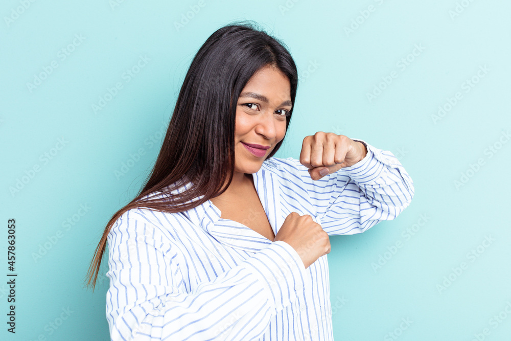 Obraz premium Young Venezuelan woman isolated on blue background throwing a punch, anger, fighting due to an argument, boxing.