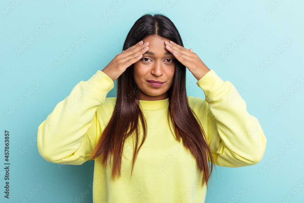 Young Venezuelan woman isolated on blue background having a head ache, touching front of the face. Young Venezuelan woman isolated on blue background having a head ache, touching front of the face.
