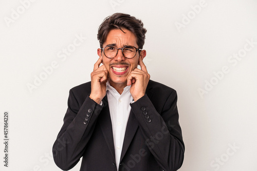 Young mixed race business man isolated on white background covering ears with hands.