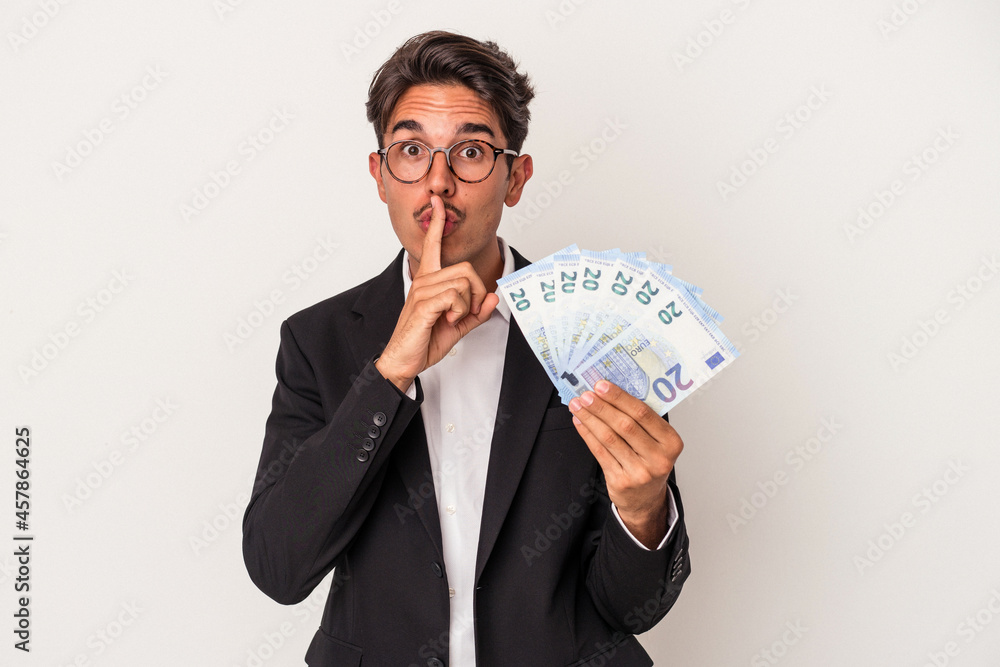 Young mixed race business man holding bills isolated on white background keeping a secret or asking for silence. Young mixed race business man holding bills isolated on white background keeping a secret or asking for silence.