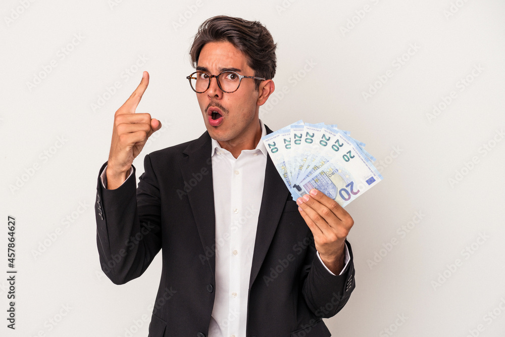 Young mixed race business man holding bills isolated on white background having an idea, inspiration concept. Young mixed race business man holding bills isolated on white background having an idea, inspiration concept.