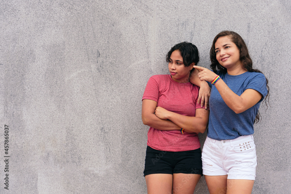 young lesbian couple standing on a city street while enjoying a day together. young lesbian couple standing on a city street while enjoying a day together.