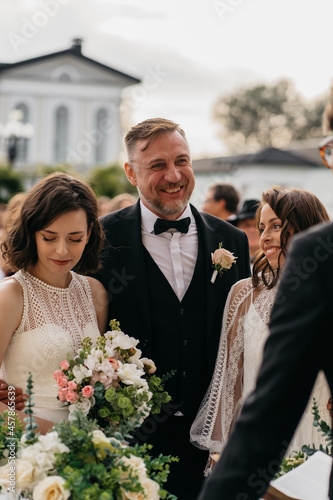 Candid shot of father walking his lesbian LGBT daughter through aisle towards her bride. Shot with 2x anamorphic lens photo