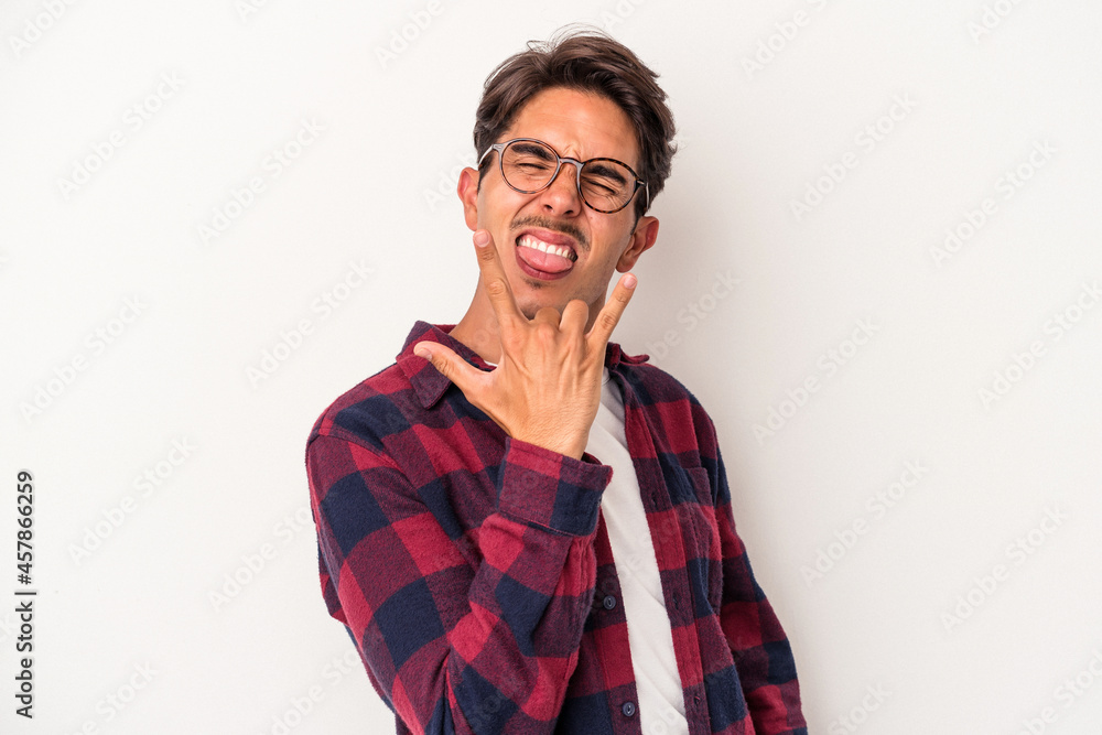 Young mixed race man isolated on white background showing rock gesture with fingers Young mixed race man isolated on white background showing rock gesture with fingers