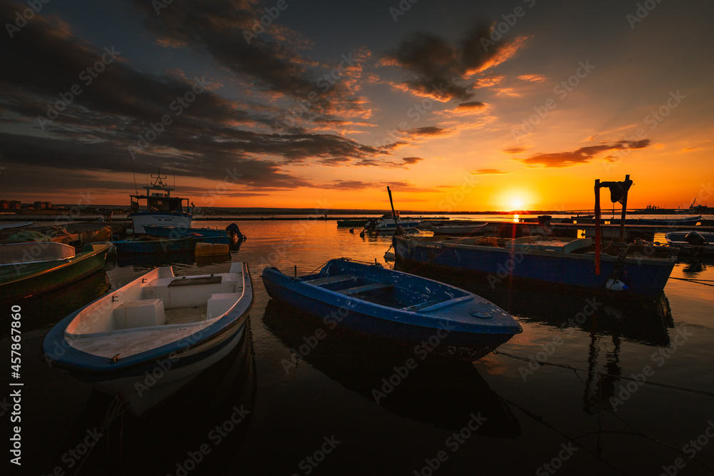 Port of the village of Taranto Vecchia at dawn with fishing boats in the foreground