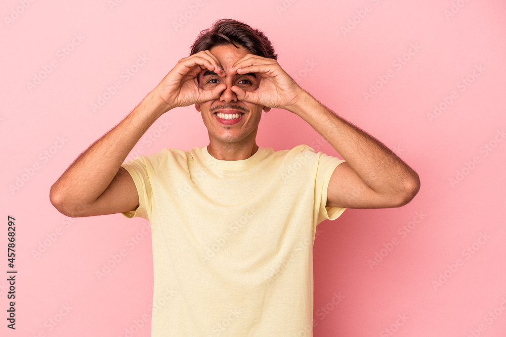 Young mixed race man isolated on white background showing okay sign over eyes Young mixed race man isolated on white background showing okay sign over eyes