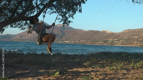 Happy woman sitting on swing on the beach. Best friends spend summer time together. The girls are happy and enjoy life. The road by car to the sea. Friendship and love forever. The beauty of Greece. photo