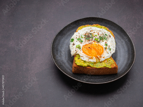 Toast with avocado and eggs served on a plate on vintage background. Top view. Space for text