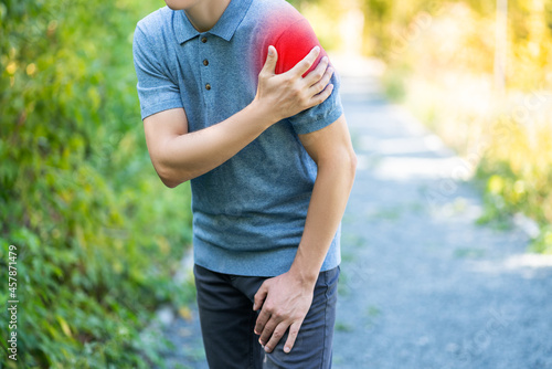 Shoulder pain when walking outdoors, man with muscle injury on nature background