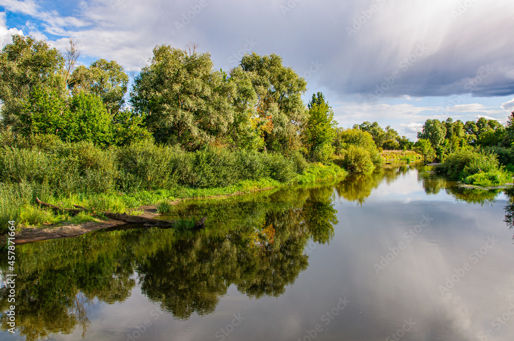 Beautiful landscape with the Teterev river in the foreground and the reflection of trees in the water Beautiful landscape with the Teterev river in the foreground and the reflection of trees in the water