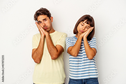 Young mixed race couple isolated on white background yawning showing a tired gesture covering mouth with hand.