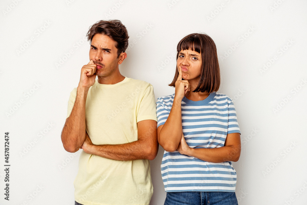 Young mixed race couple isolated on white background unhappy looking in camera with sarcastic expression. Young mixed race couple isolated on white background unhappy looking in camera with sarcastic expression.