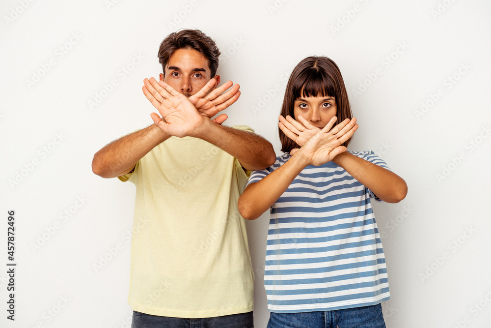 Young mixed race couple isolated on white background doing a denial gesture Young mixed race couple isolated on white background doing a denial gesture