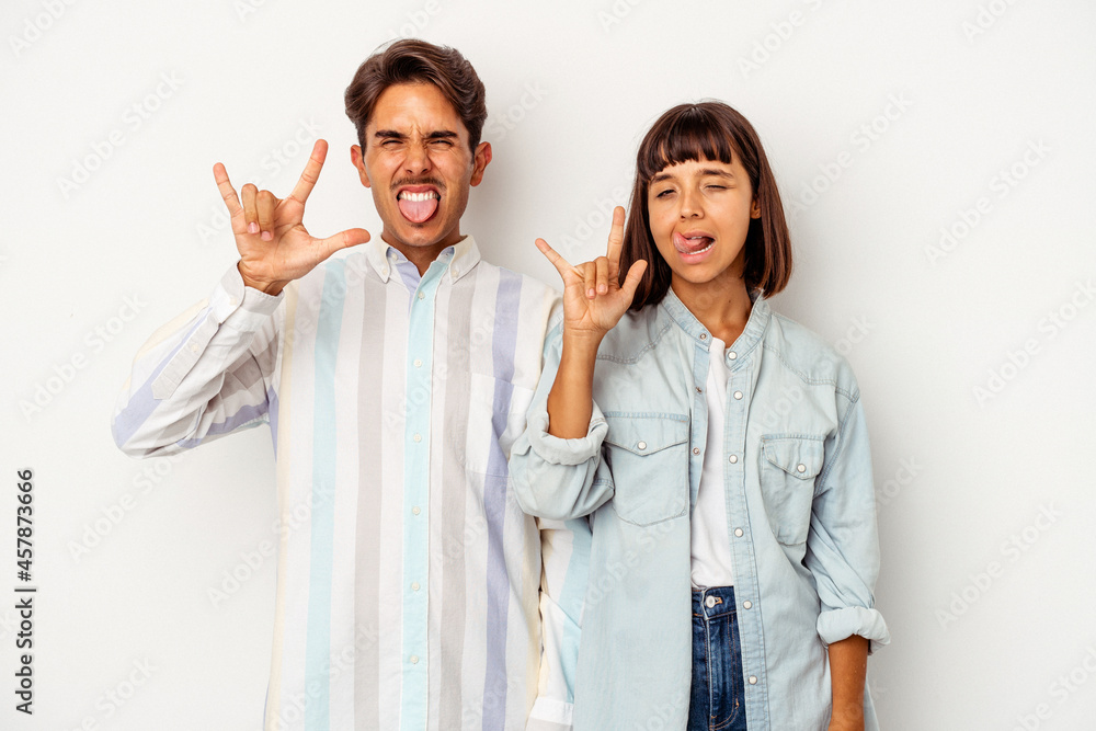 Young mixed race couple isolated on white background showing rock gesture with fingers Young mixed race couple isolated on white background showing rock gesture with fingers