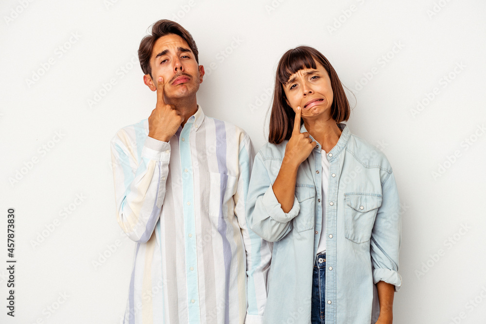Young mixed race couple isolated on white background crying, unhappy with something, agony and confusion concept. Young mixed race couple isolated on white background crying, unhappy with something, agony and confusion concept.